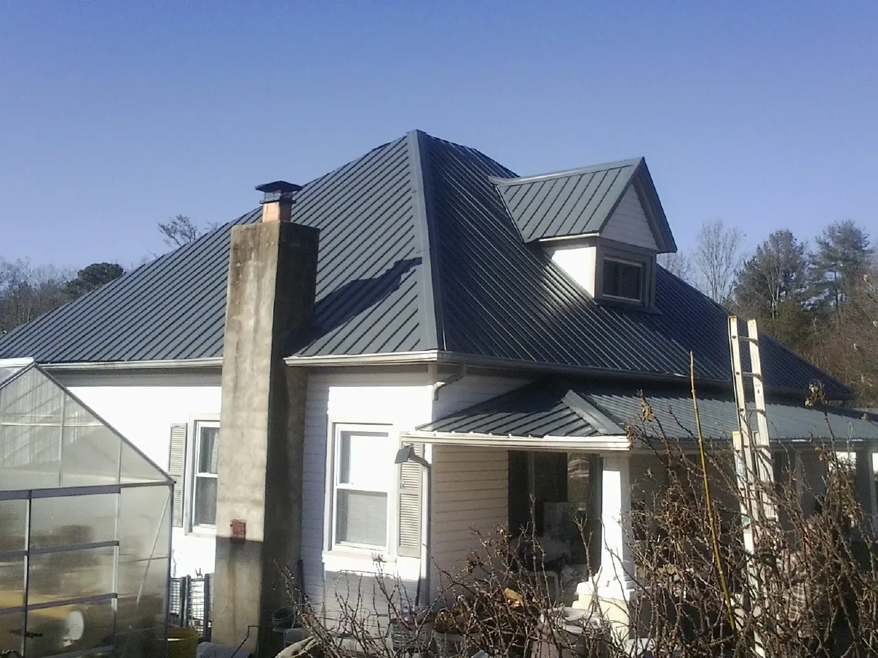 Dark blue standing seam metal roof on a white farmhouse with dormer — Slate & Tile Roof Repair by Roofing Brothers in Jeannette