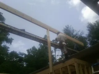 Carpenter setting a ridge beam over a new addition frame — Ice Dam Removal by Roofing Brothers in Jeannette