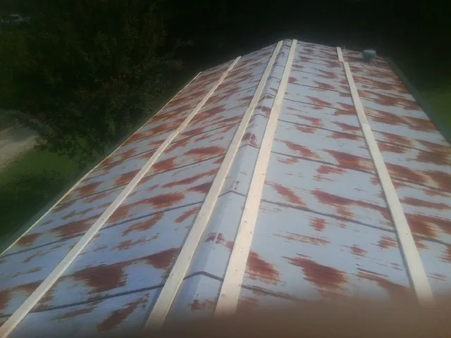 Rusted metal roof panels with new wood purlins before replacement — Storm Damage Roof Repair in Jeannette by Roofing Brothers