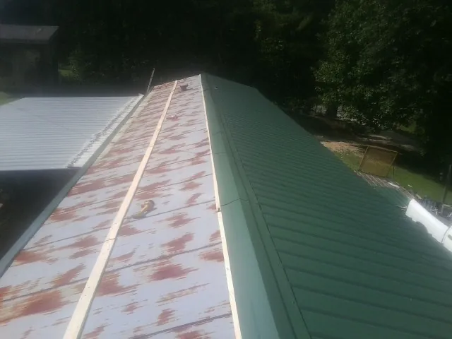 Old rusted panels beside newly installed green metal roofing — Wind Damage Roof Repair by Roofing Brothers in Jeannette