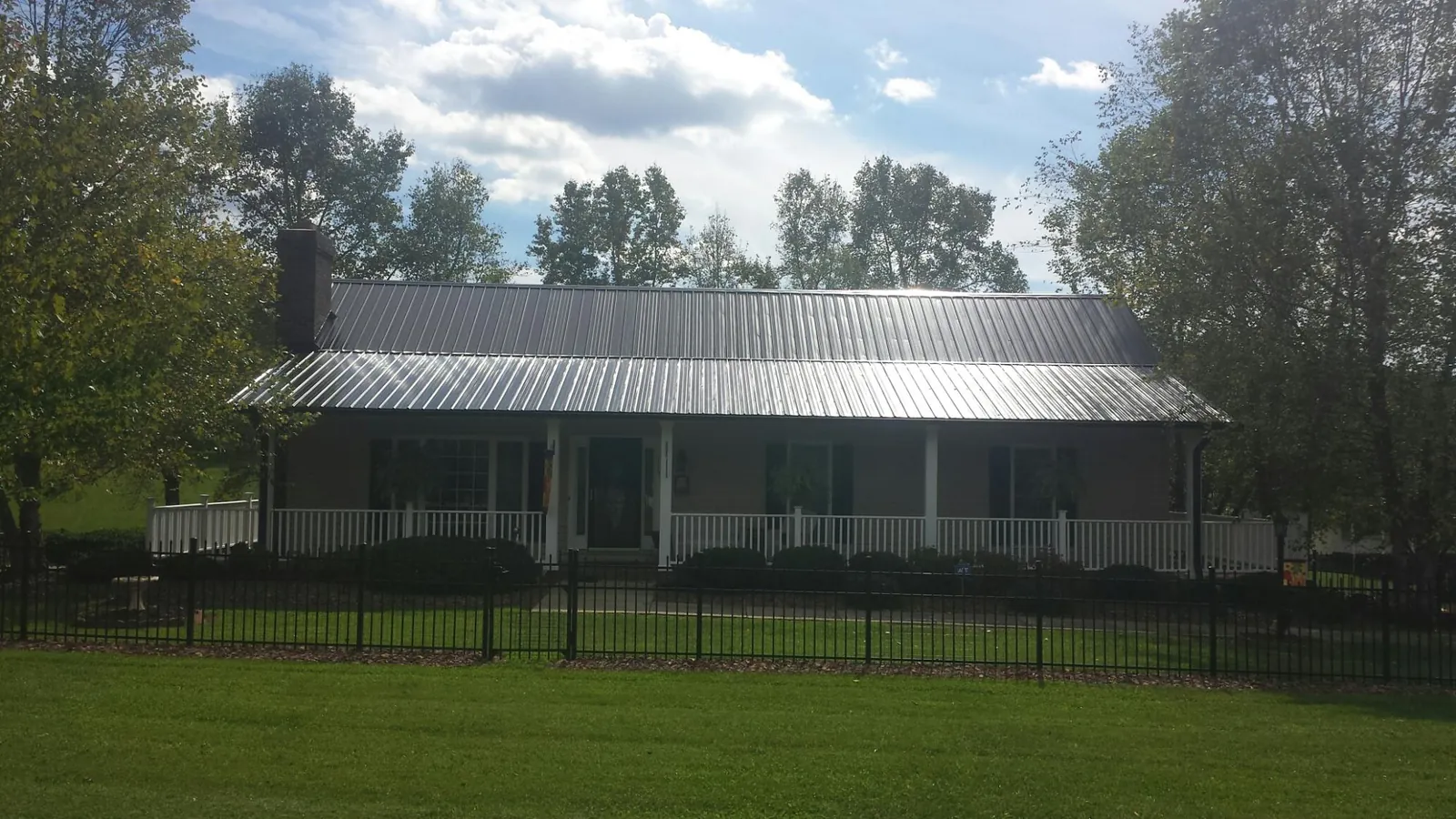 Gray metal roof on a brick ranch with a full width front porch — Gutter Guard Installation work by our crew in Jeannette