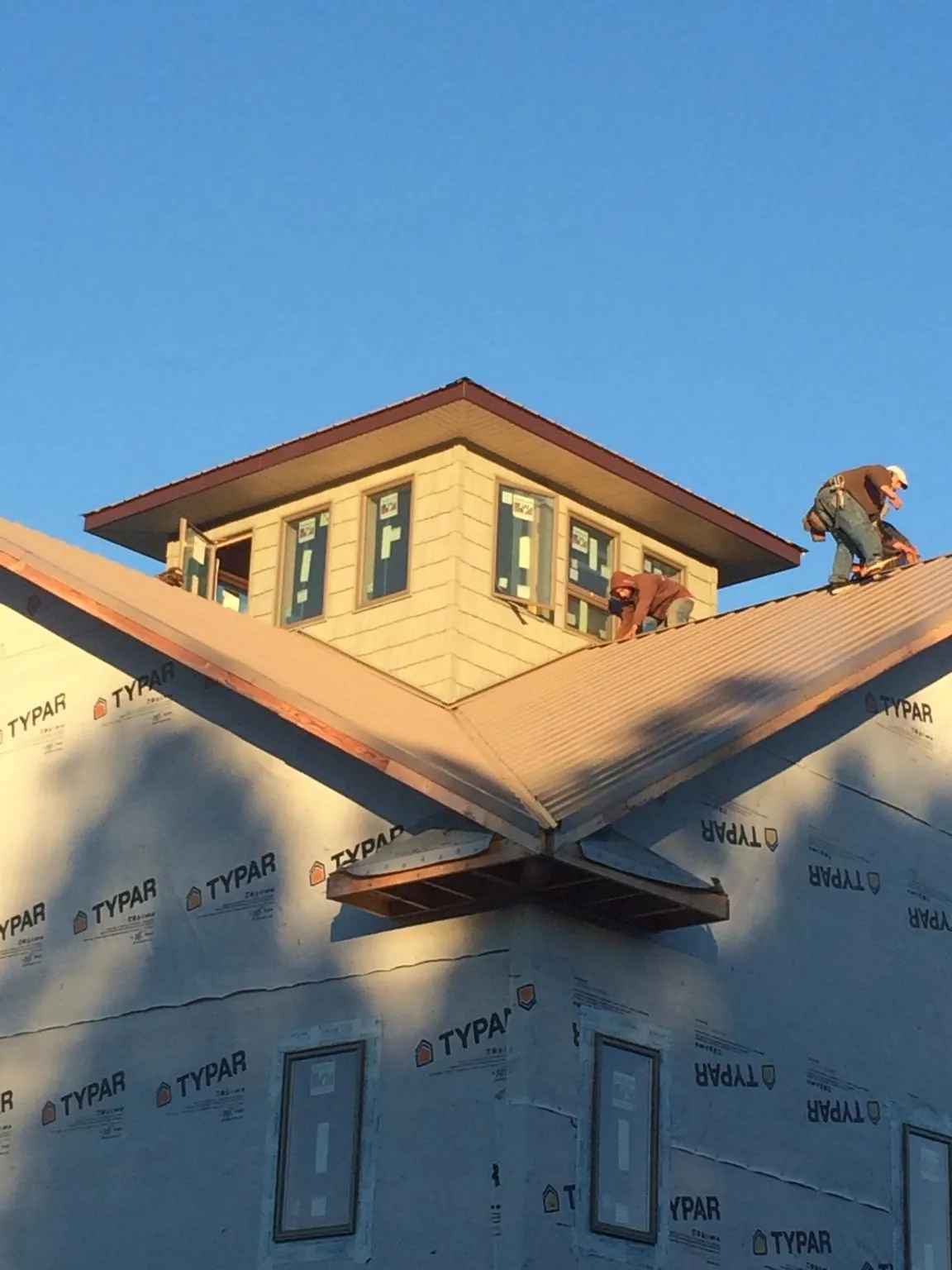 Roofers working around a rooftop cupola on a new metal roof at sunset — Roof Waterproofing in Jeannette by Roofing Brothers